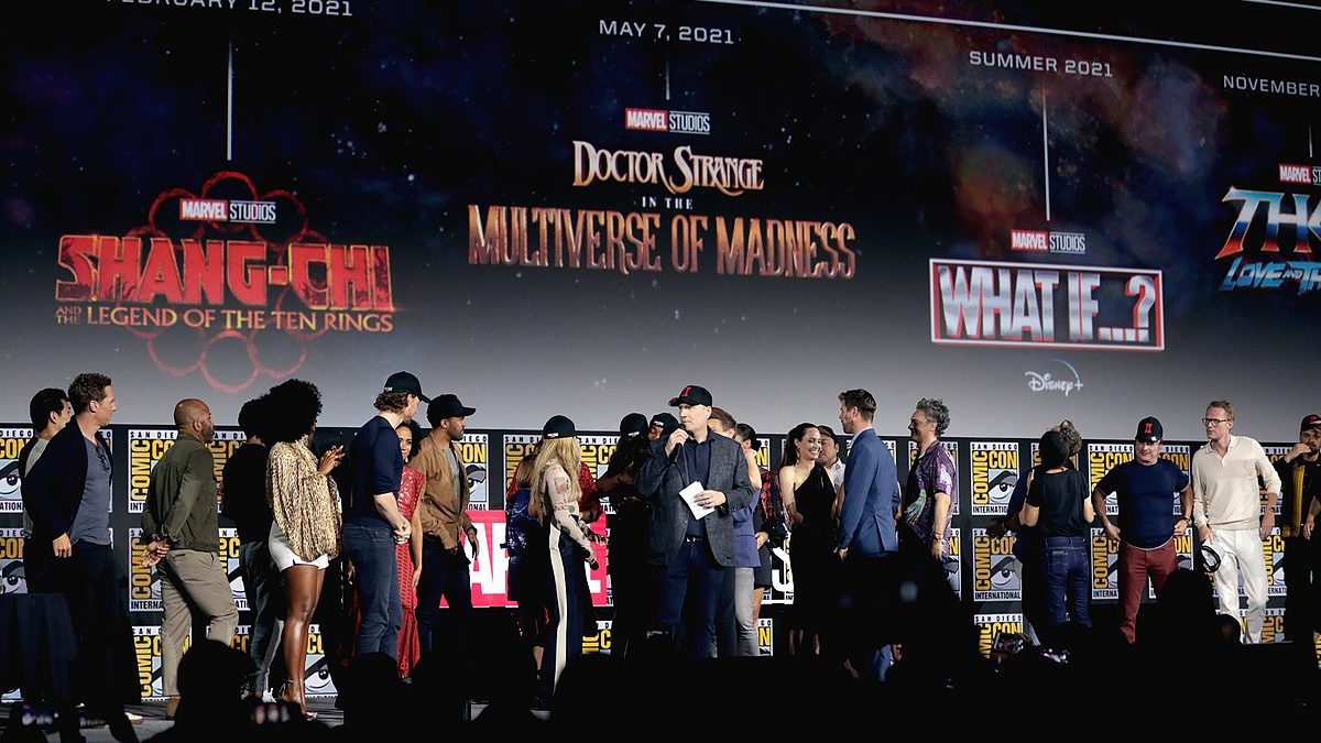 Various actors who play characters in Marvel movies are on stage. Behind them, there is a screen with a timeline of the release dates of Marvel movies and television series.