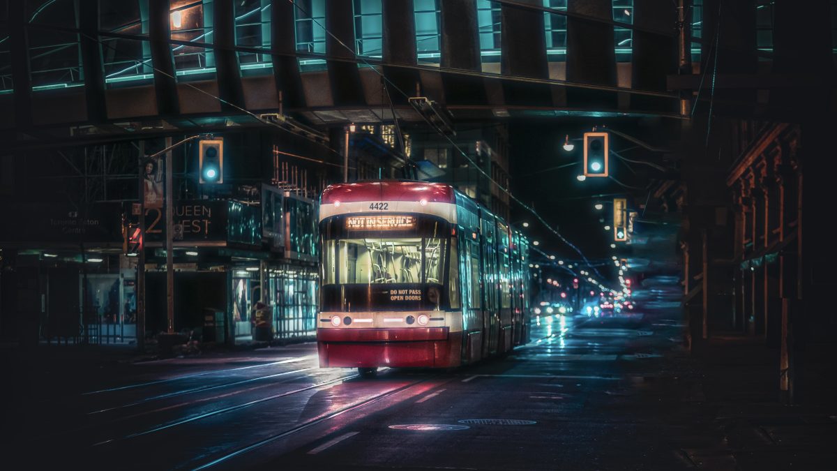 A Red Streetcar Moving on the Road During Night Time