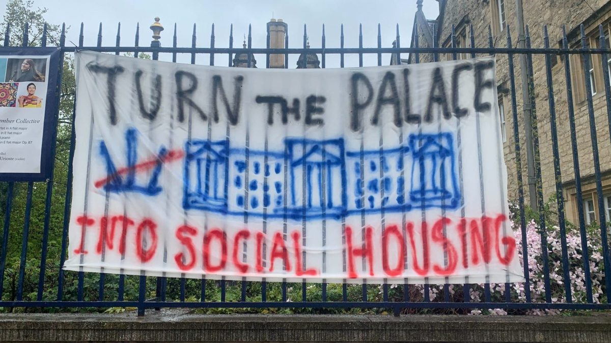 Photo of a banner reading "Turn the Palace into Social Housing" attached to Trinity College.