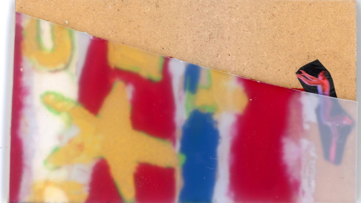 An abstract art piece. A printed picture of a man is sandwiched between a cork background and a layer of perspex on the far right on the piece. Abstract shapes in yellow, red, and blue can be seen to the left of the man.