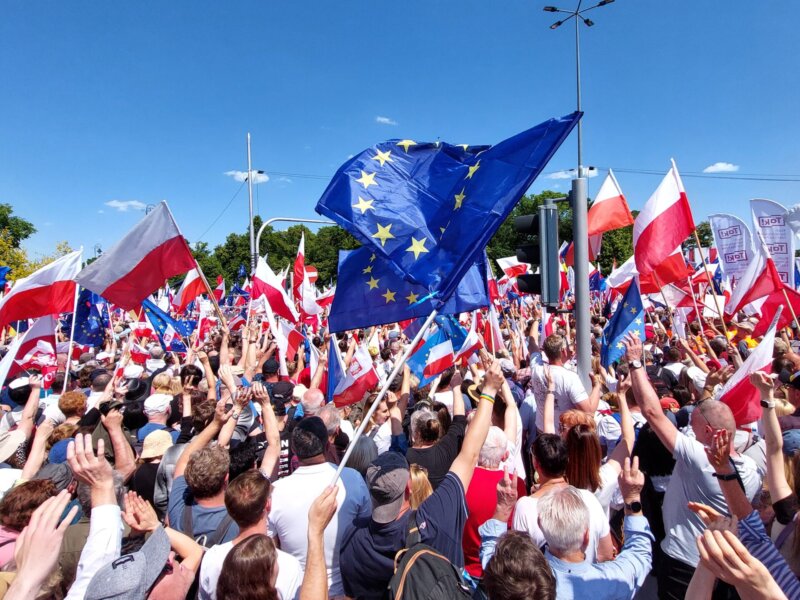 Participants at a Polish opposition rally wave Polish and EU flags.