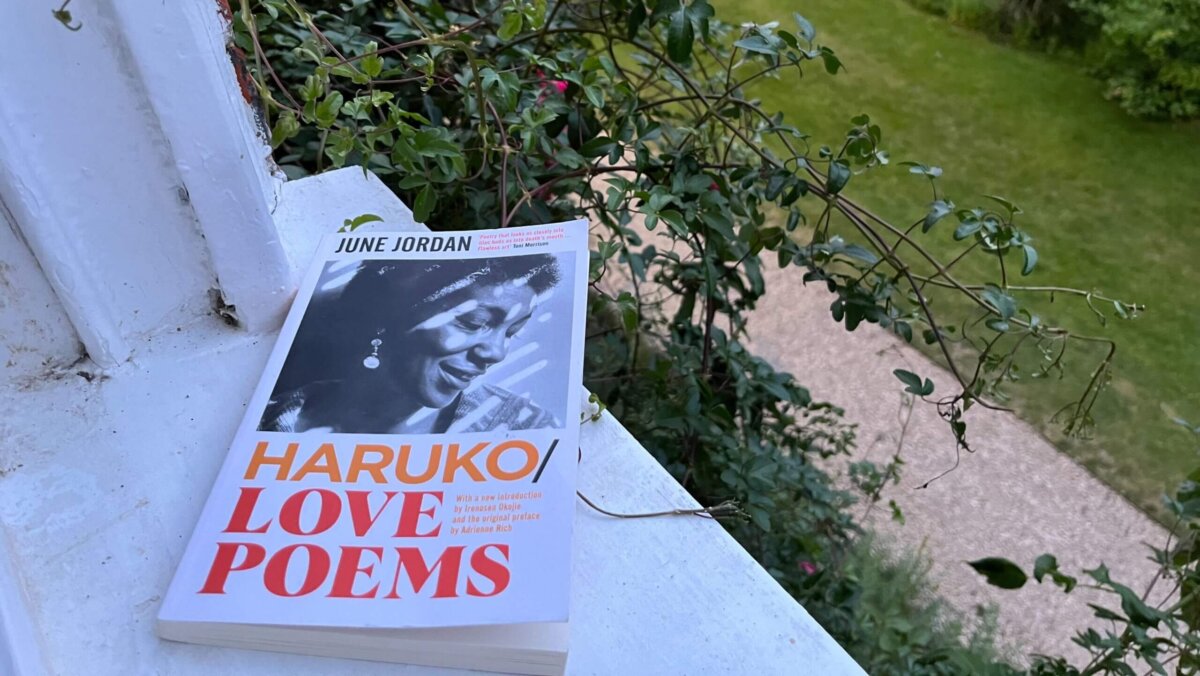 A copy of June Jordan's poetry collection 'Haruko/Love Poems' placed on a windowsill overlooking a garden.
