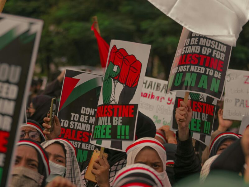 Picture of protestors, standing in solidarity with Palestine, holding posters with the words 'free Palestine' on them