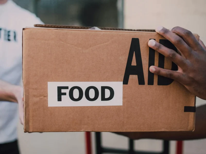 A picture of one person passing someone a box labelled 'food aid'.