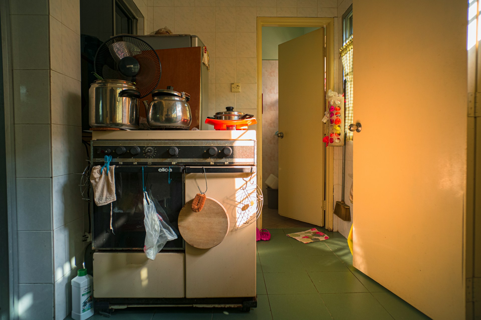 A messy kitchen. To the left is a stove with applicances on it. To the right is an open door leading into another room.