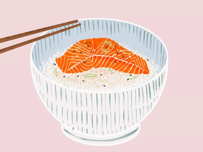 A slide of orange salmon on a bed of rice, in a white bowl, on a pink background, with two chopsticks resting on the lip of the bowl.
