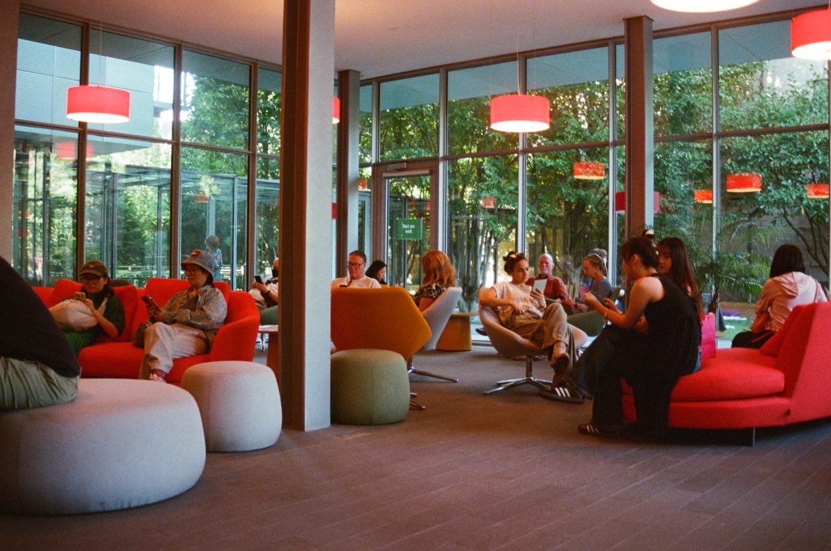 A picture of people in a library common room. Everyone is looking at their phones.
