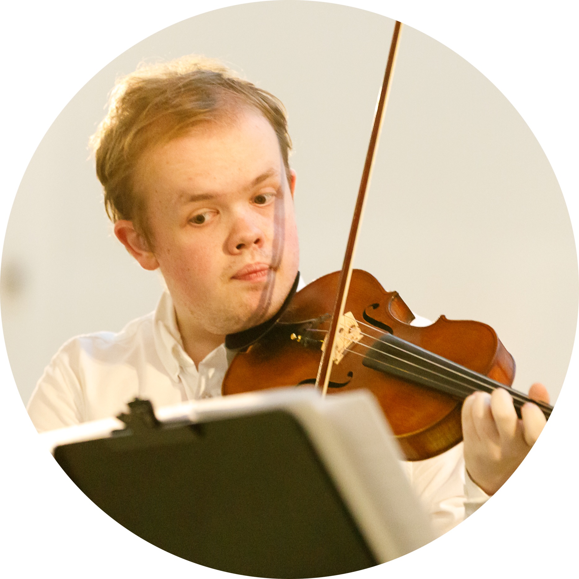 Image depicts Samuel Oliver-Sherry holding a violin and looking at sheet music on a music stand