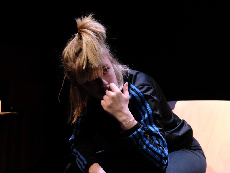 A photo of a cast member sat leaning forward on set