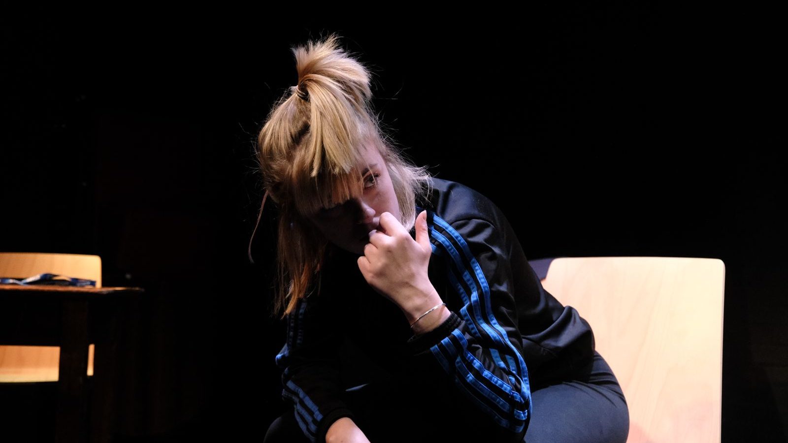 A photo of a cast member sat leaning forward on set