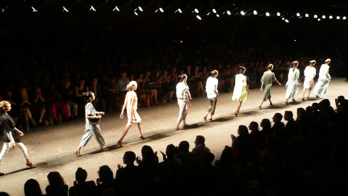 A photo of models walking across a runway at a fashion show
