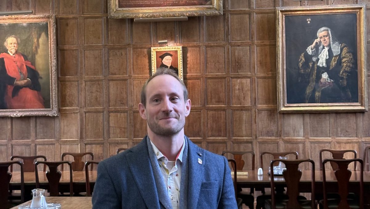 Dr. Matt Williams stands in the hall of Jesus College, Oxford.
