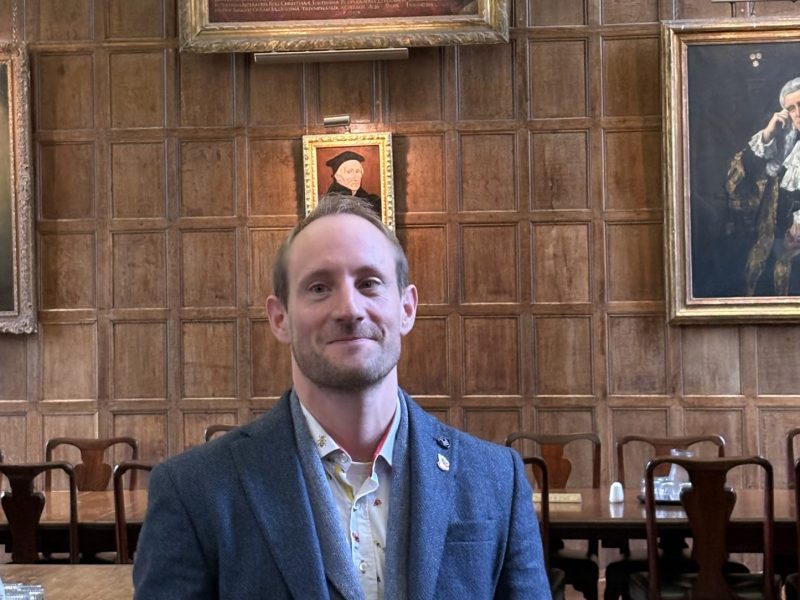 Dr. Matt Williams stands in the hall of Jesus College, Oxford.