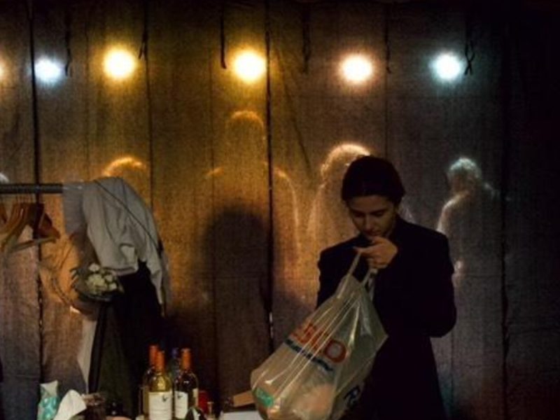 character looks through a bag while on stage