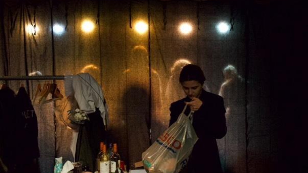 character looks through a bag while on stage