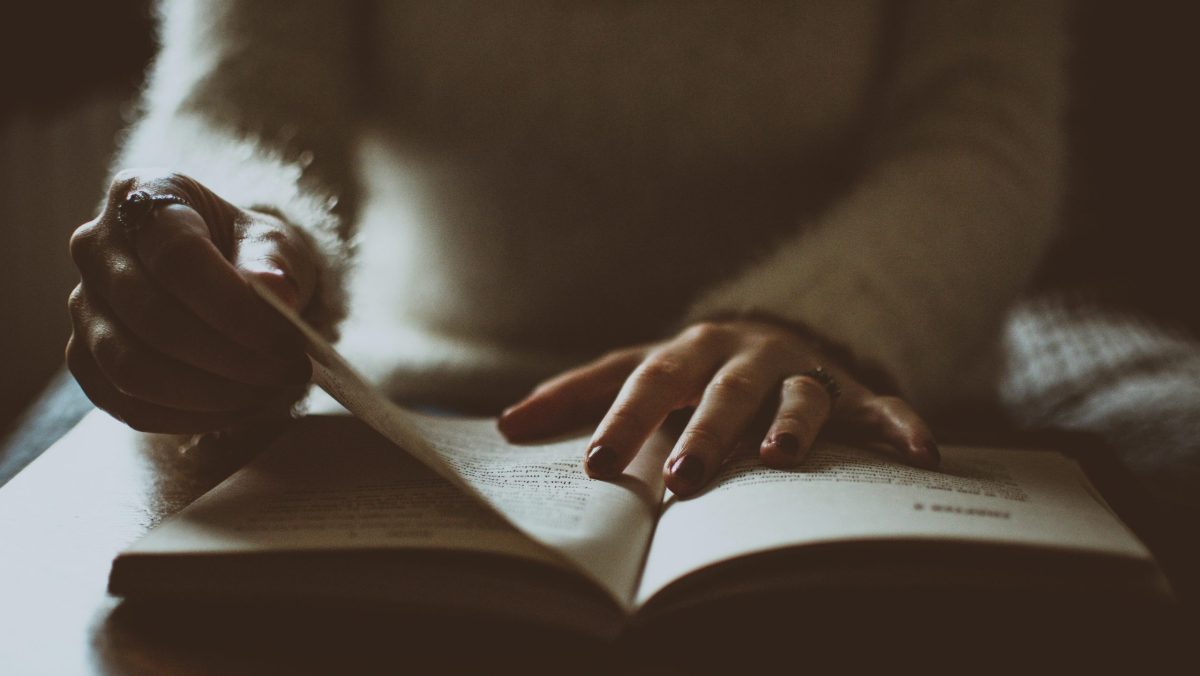 Photo of somebody alone flipping a book.