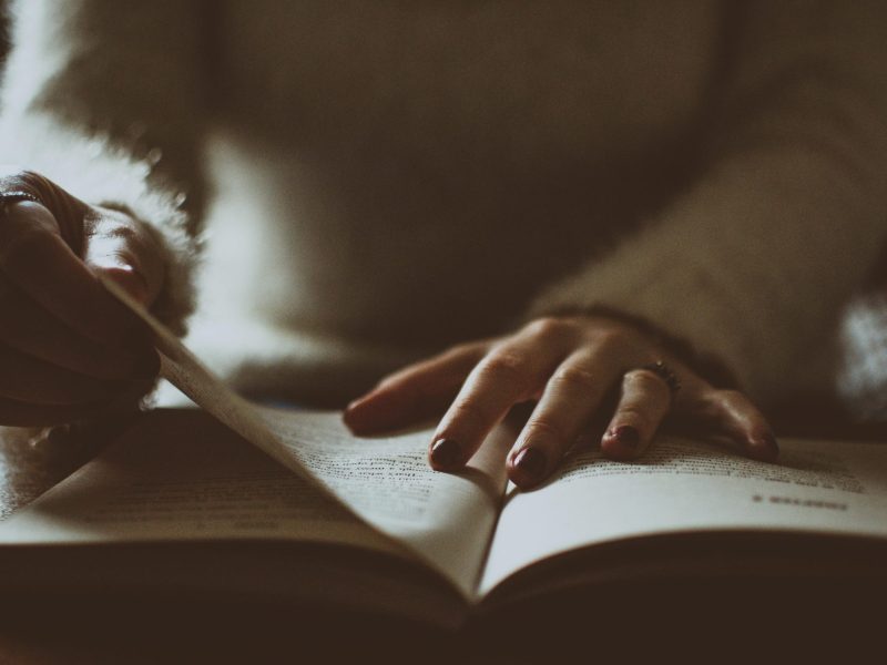 Photo of somebody alone flipping a book.