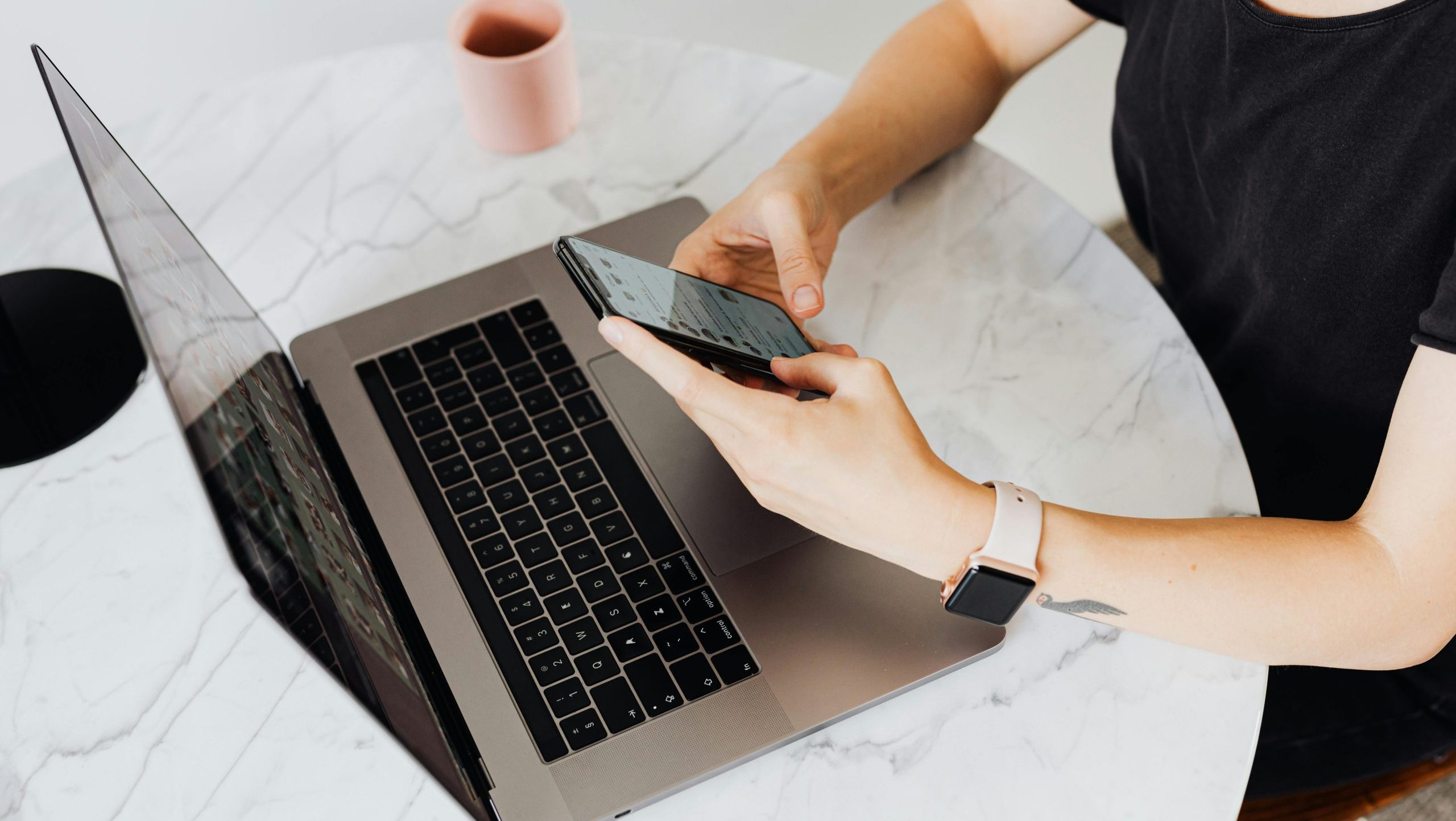 Photo of a woman using a phone and a laptop.