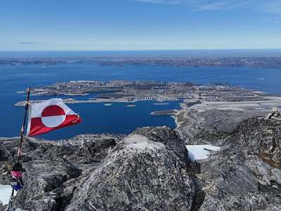 A picture of the flag of Greenland towering over the landscape.