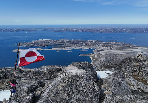 A picture of the flag of Greenland towering over the landscape.