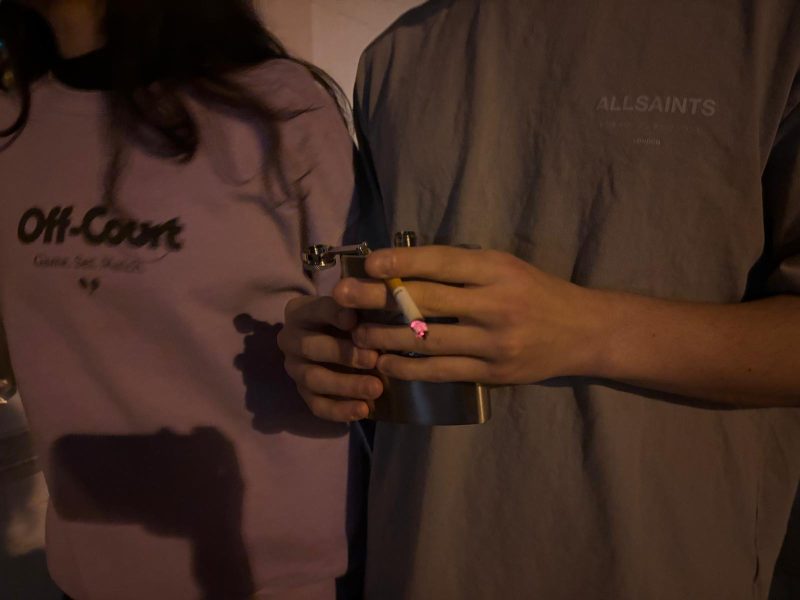 Two figures, one of them holding a cigarette