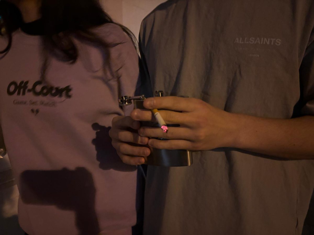 Two figures, one of them holding a cigarette