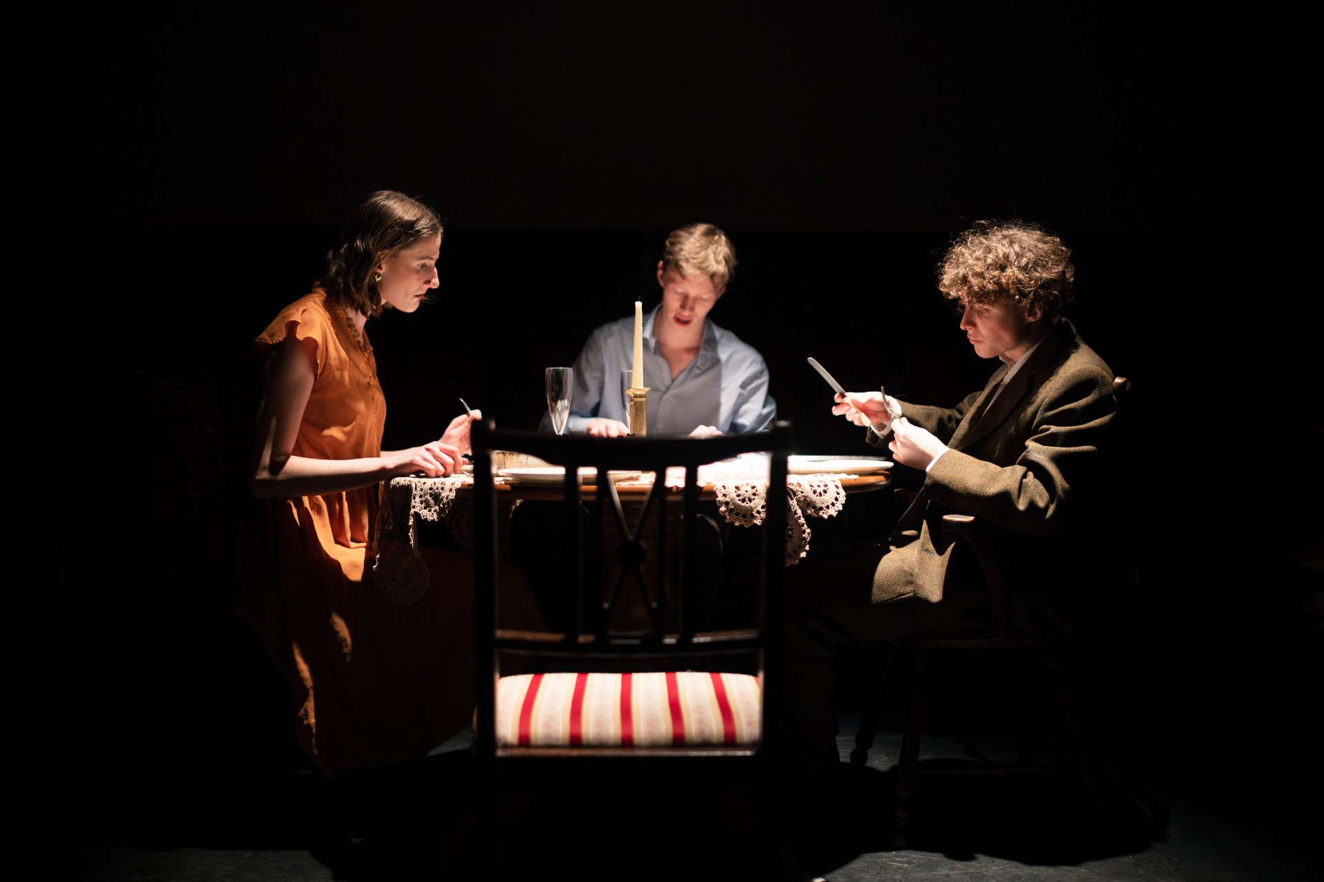 Three characters from the Glass Menagerie sit around a table.