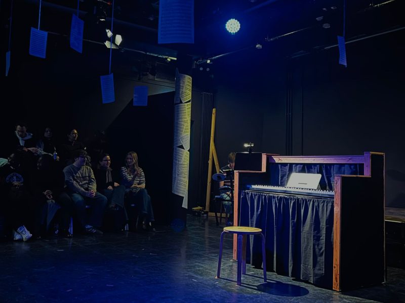 A theatre in the centre of a theatre set. The audience are waiting.