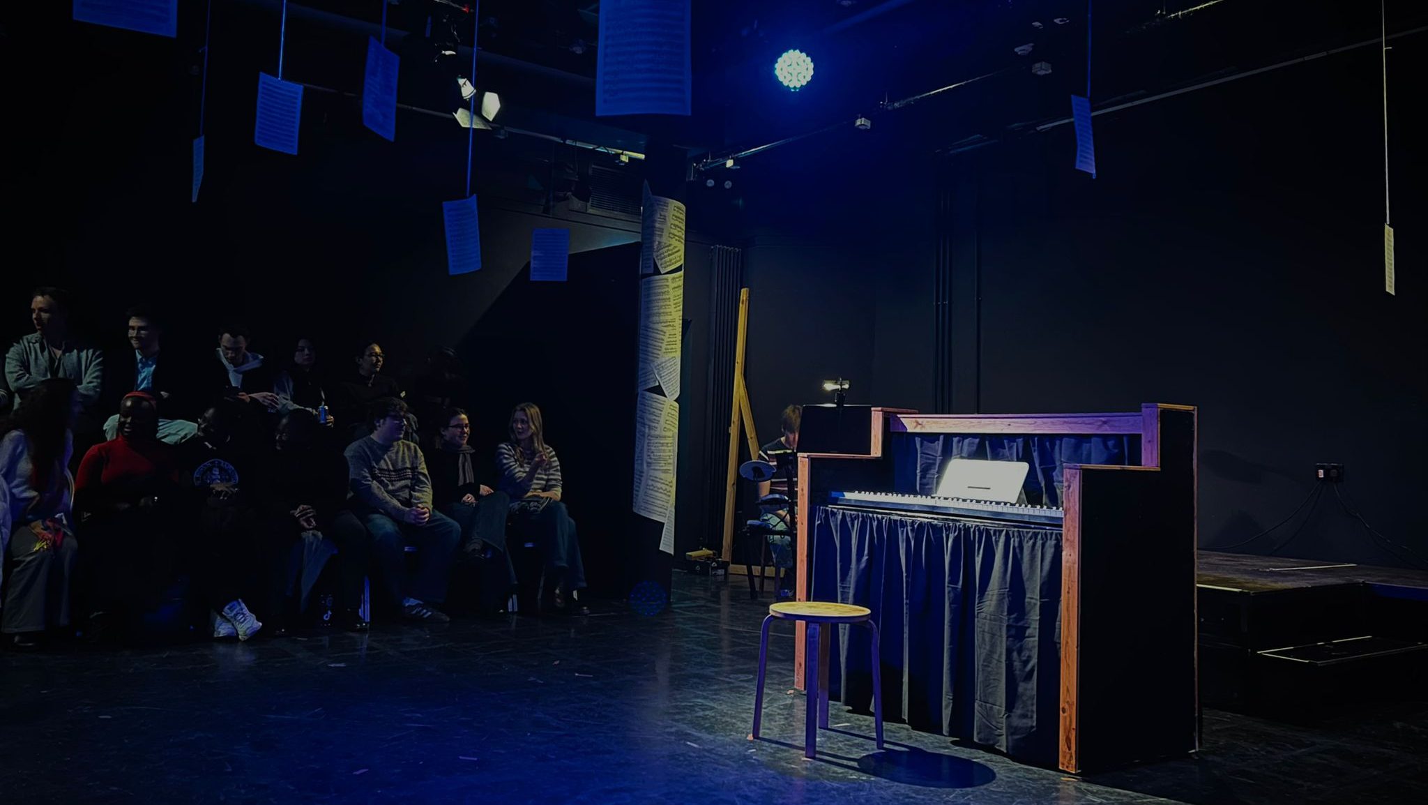 A theatre in the centre of a theatre set. The audience are waiting.