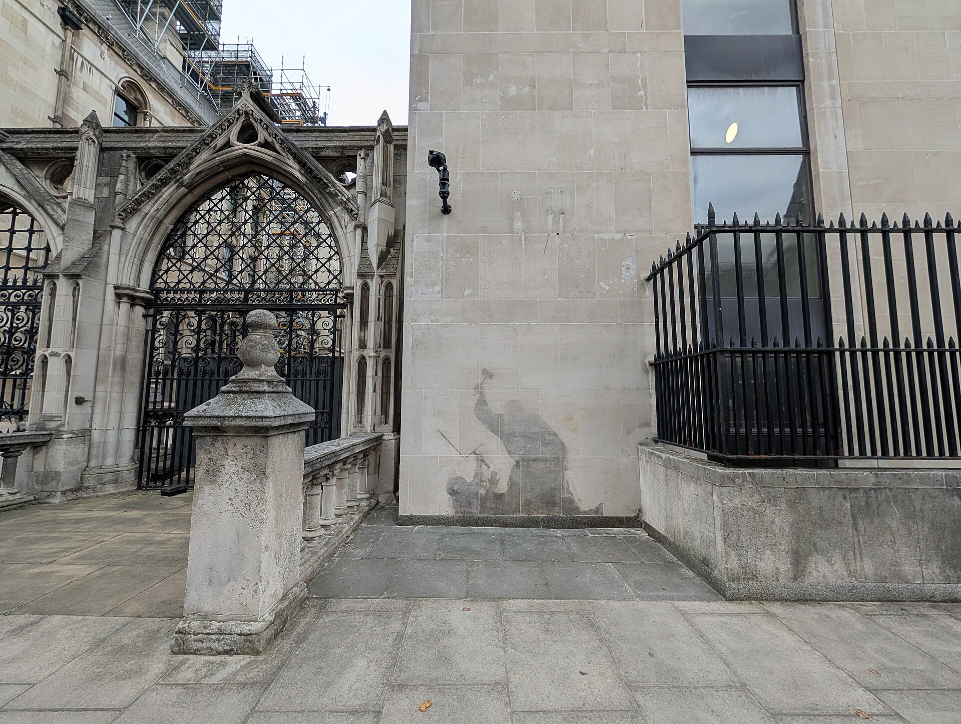A Banksy stencil showing a judge beating a protester with a gavel on the Royal Courts of Justice in London.