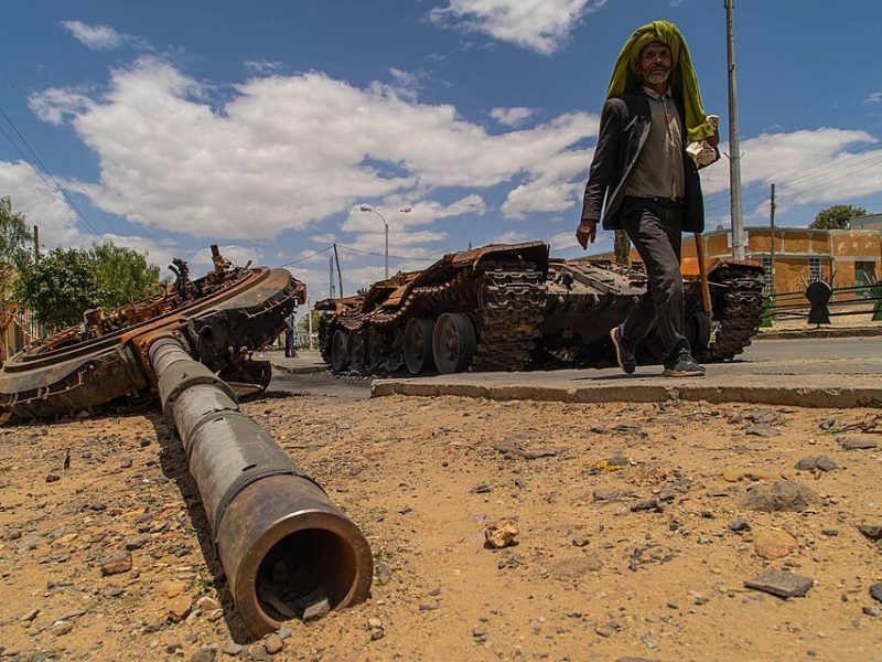 A man walks past a wrecked tank in Tigray Region, 2021.