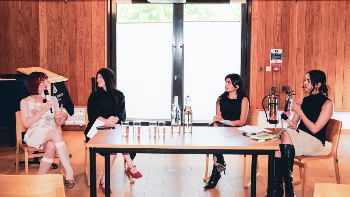 Four women sit at a table talking.