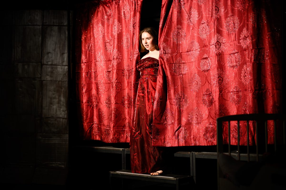 Lady Carla (Genevieve Kidd) pokes out from behind the curtain
