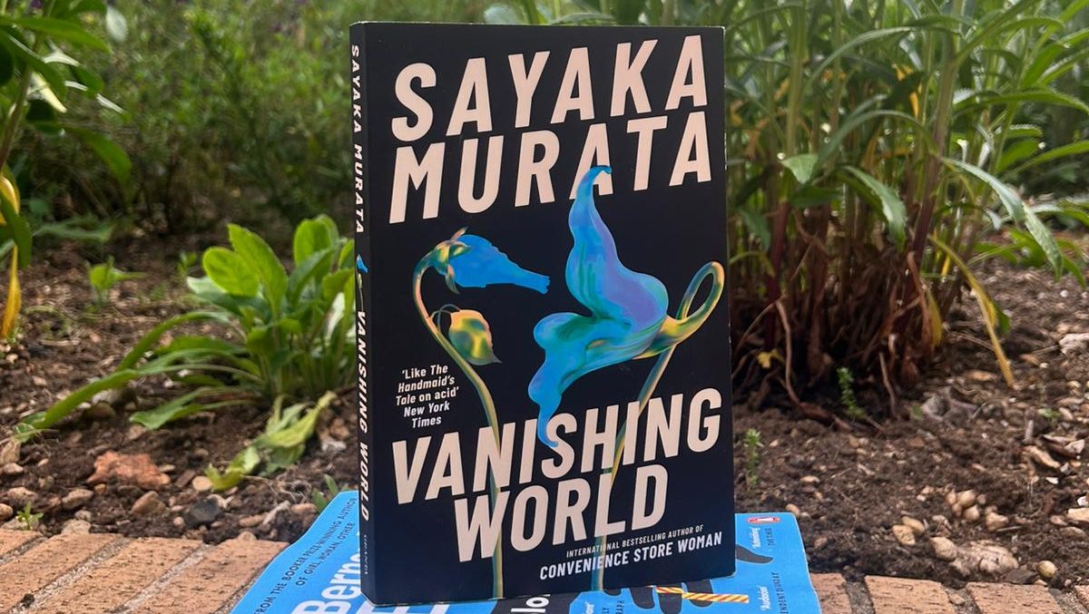 Three books in a pile in front of plants