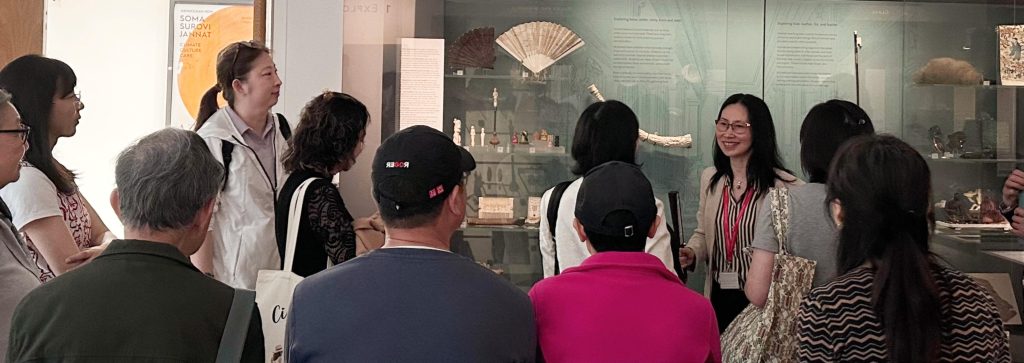 An image of museum-goers being shown Chinese fans in the Ashmolean Museum.
