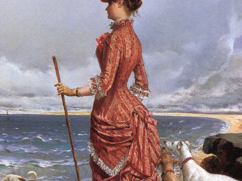 An elegant, old-fashioned lady walking her dogs along a beach