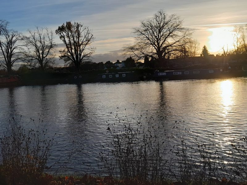 Sun setting over a river with trees on the far side