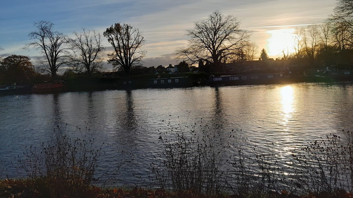 Sun setting over a river with trees on the far side