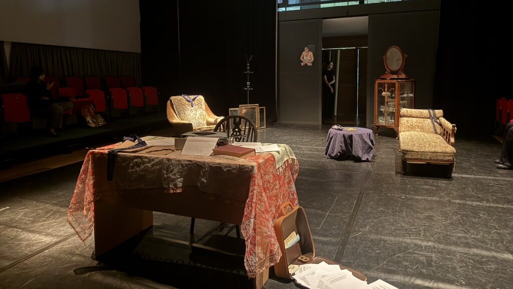 Keble O'Reilly Theatre, set with a desk, a sofa, and a chair, with scattered paper on the floor.