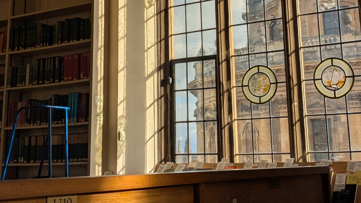 A desk in front a window which looks out onto the Radcliffe Camera
