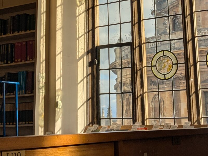 A desk in front a window which looks out onto the Radcliffe Camera