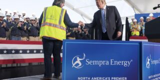 Image is of President Donald Trump shaking hands with a Cameron LNG representative on stage.