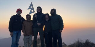 4 people stood on a mountain in Nepal at sunrise