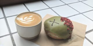 A coffee and an artsy doughnut sit on a countertop.