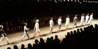 A photo of models walking across a runway at a fashion show
