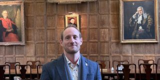 Dr. Matt Williams stands in the hall of Jesus College, Oxford.