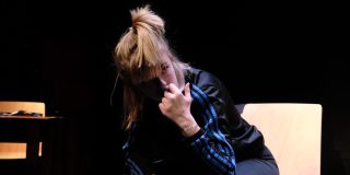 A photo of a cast member sat leaning forward on set