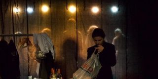 character looks through a bag while on stage