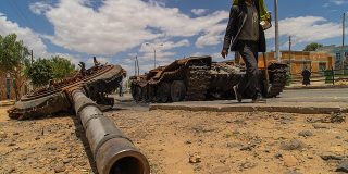 A man walks past a wrecked tank in Tigray Region, 2021.