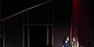 A student theatre set with two actors and a wooden structure which looks like a house.